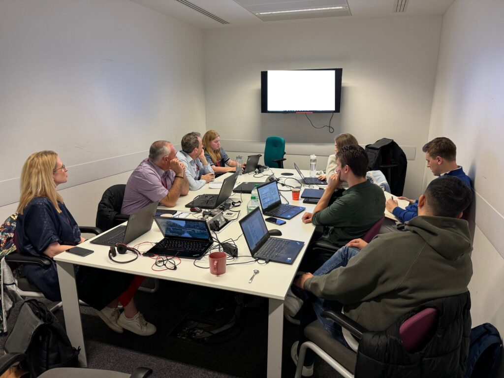 This image shows the redaction team sitting in a boardroom with their laptops collaboratively working together 