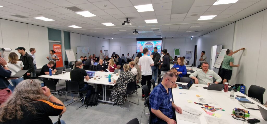 This image shows a landscape view of a room full of attendees during the morning of the hack-a-thon