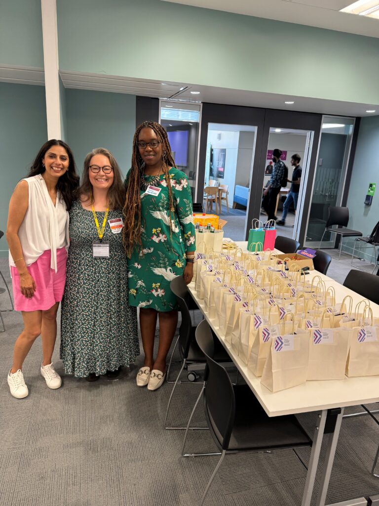 This image shows three of the FoundryLive event team standing next to the goody bags that were handed to event attendees after day two